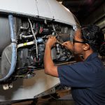 Student completing maintenance on a plane