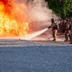 Three fire fighters putting out a fire during fire training exercises.