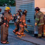 A group of firefighters entering a smoke filled building for a training exercise.