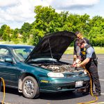 Officer assisting a student with jump start of vehicle.