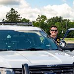 Officer beside patrol car.