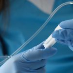 Female nurse hand in blue protective gloves hold dropper