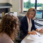 Two women sitting at desk working on a document