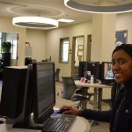 Student at computer station in Financial Aid Office, smiling