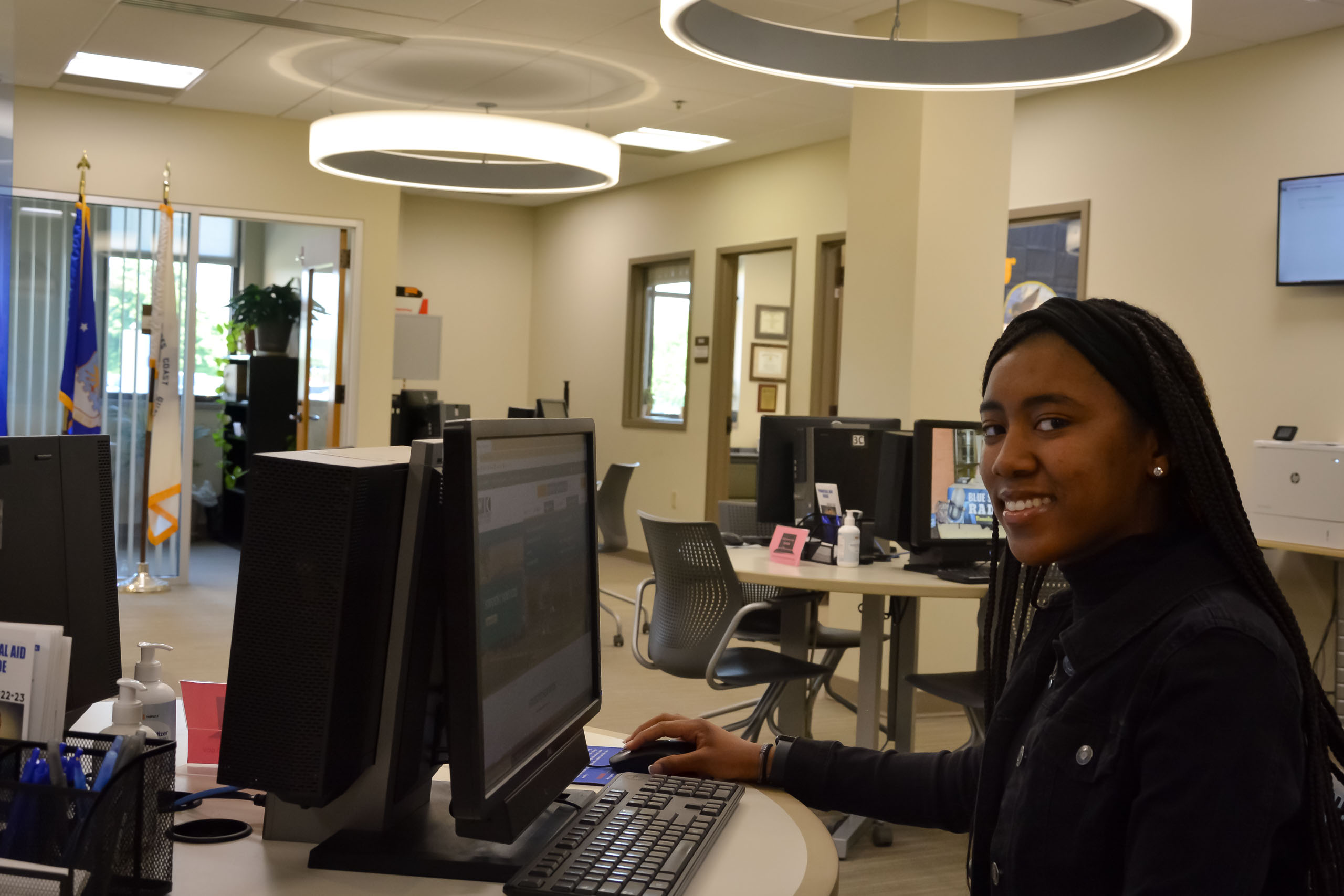 Student at computer station in Financial Aid Office, smiling