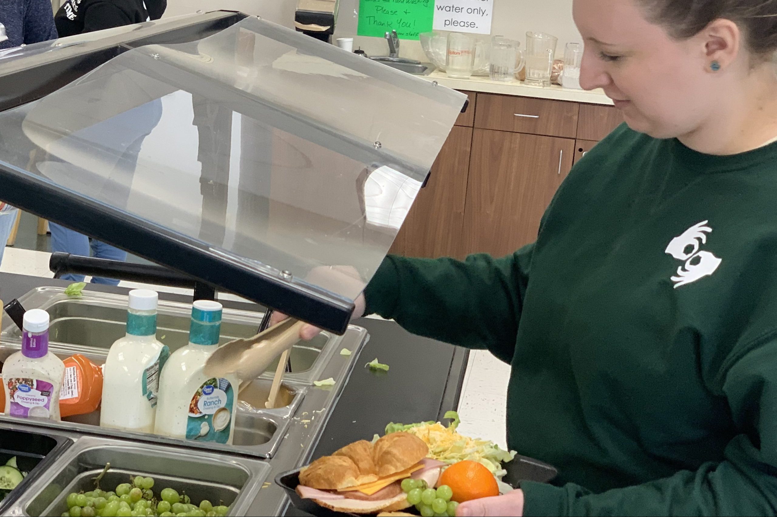 Sign language student serving themselves lunch at the cafeteria.